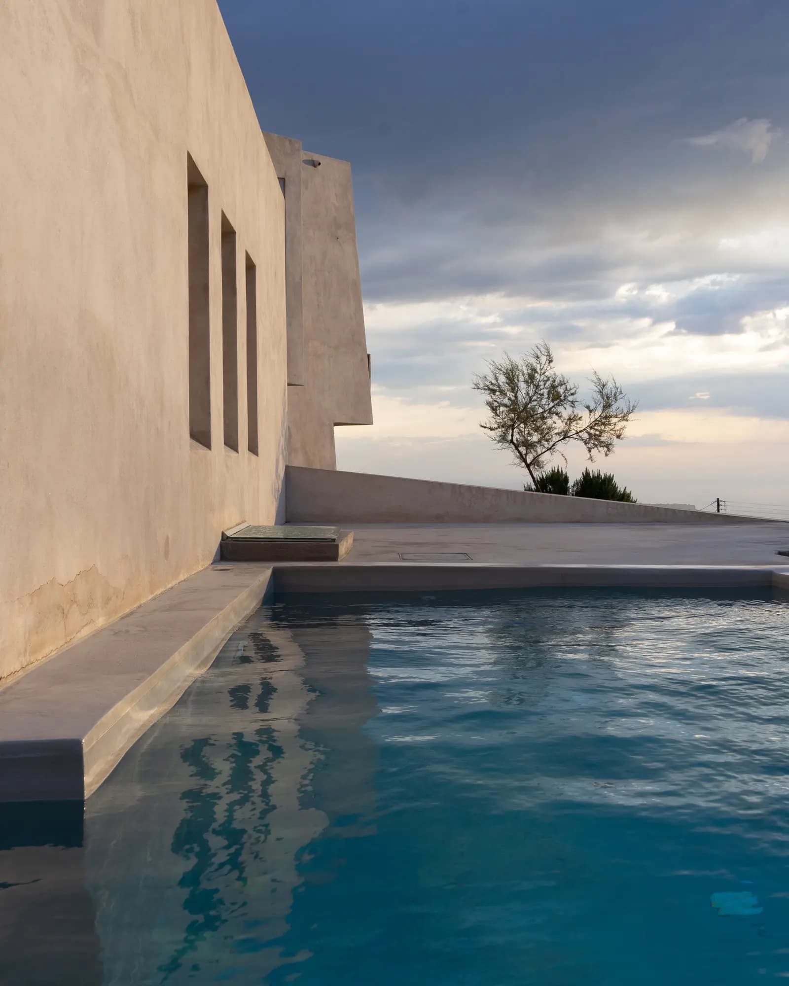 Contemporary concrete residence and pool under an evening sky