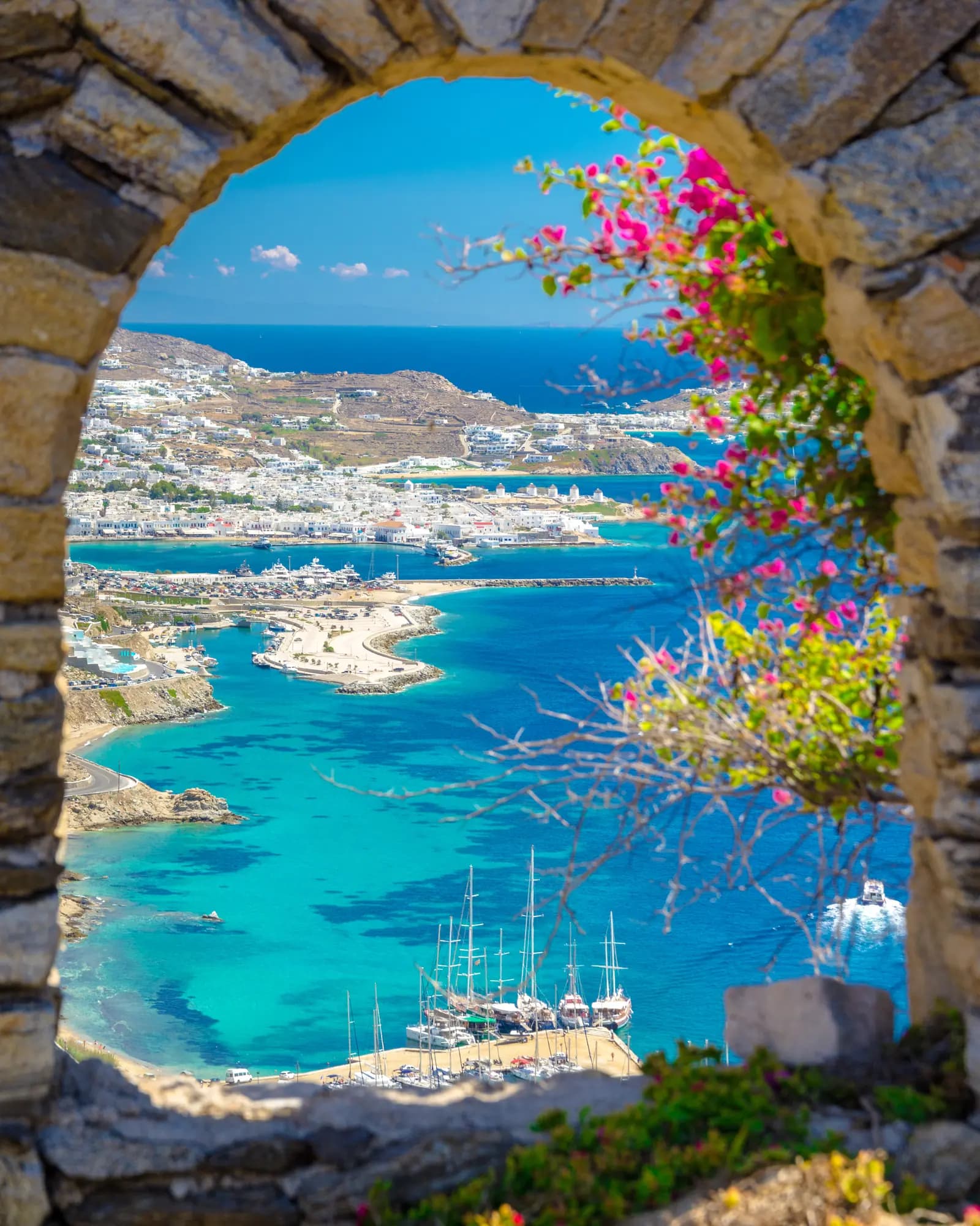 Bougainvillea arch framing a bright Greek bay