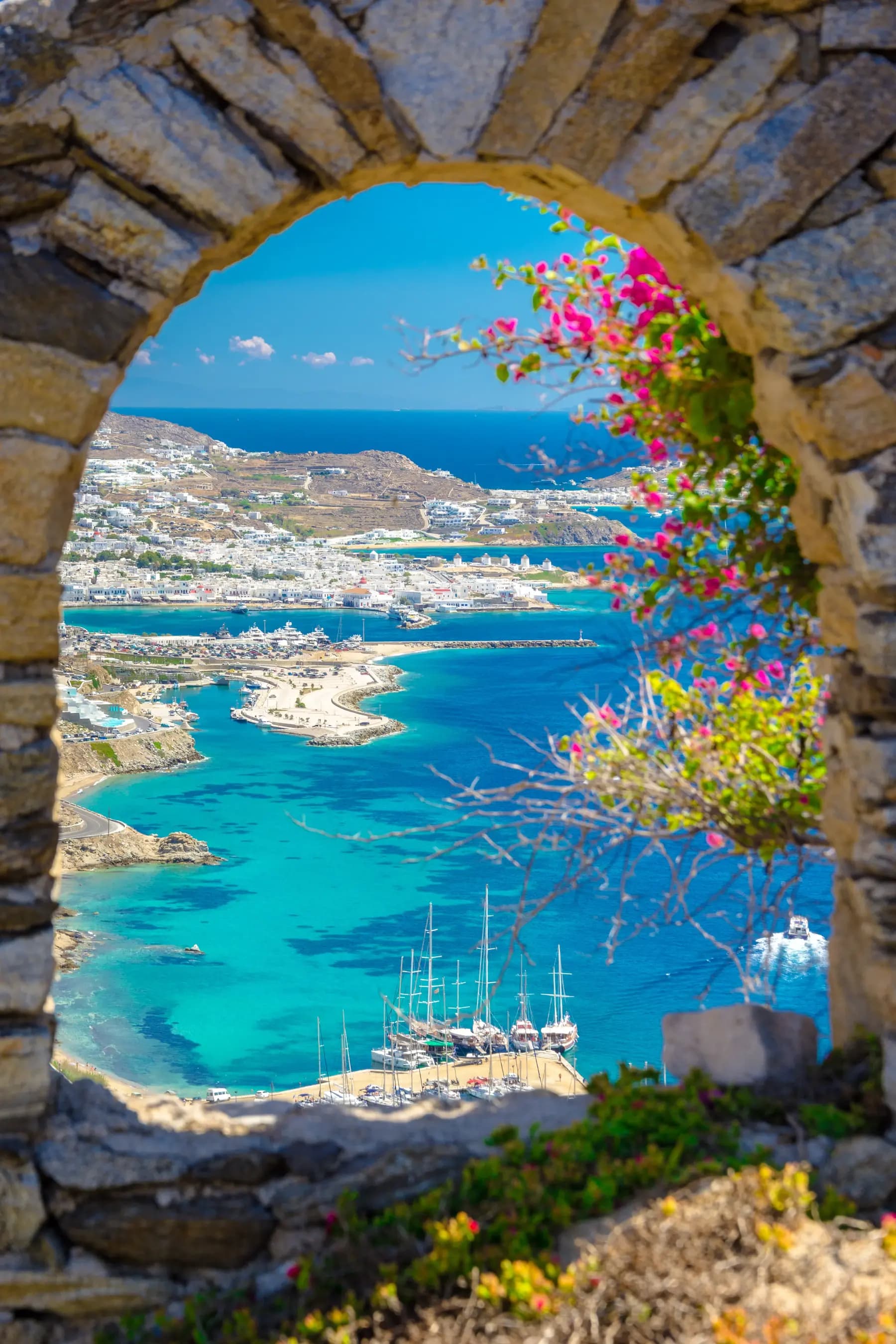 Bougainvillea arch framing a bright Greek bay
